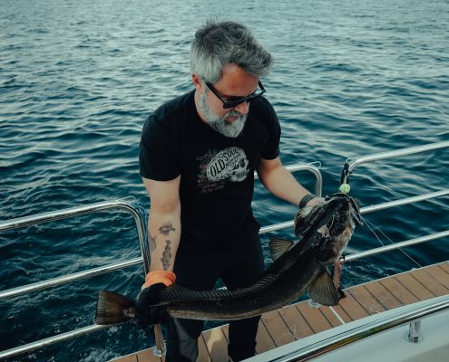 Guest reeling in a fresh catch during a fjord fishing tour near Bergen.