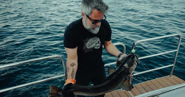 Guest reeling in a fresh catch during a fjord fishing tour near Bergen.